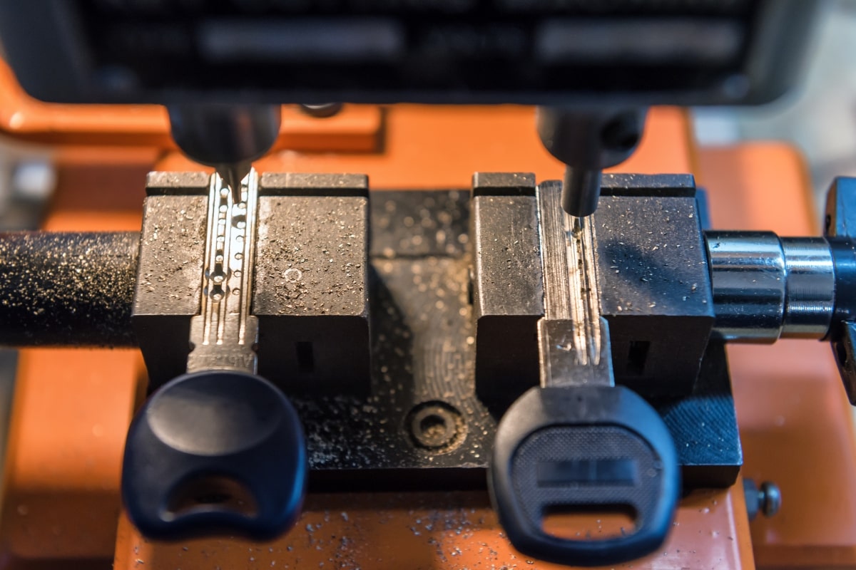 This image showcases a key cutting machine and a set of transponder keys, which are essential components of modern car security systems.