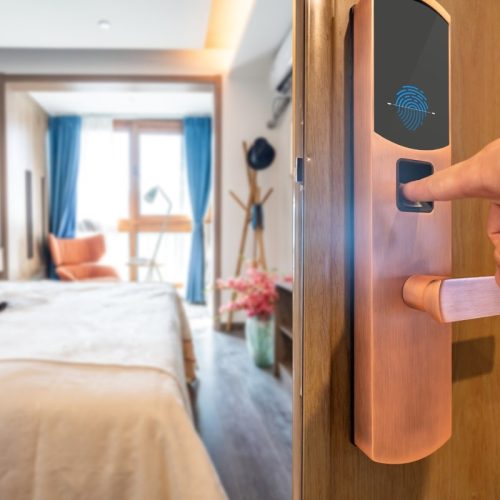 A close-up of a modern digital door lock with a fingerprint recognition panel engaged by a person's finger, highlighting the ease of access and security for a home.