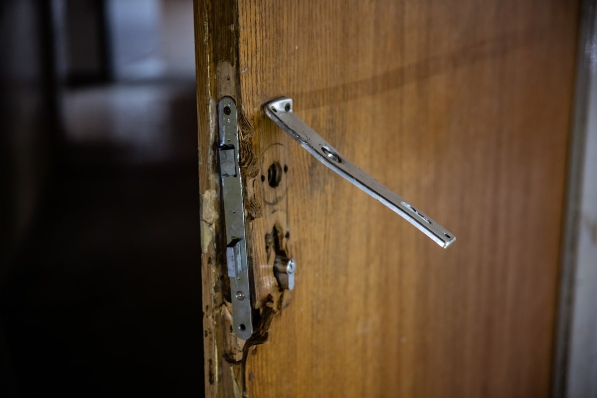 A close-up of a compromised door lock with visible signs of forced entry, highlighting the necessity for the durability and reliability of deadlocks.