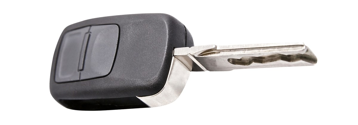 A close-up image of a transponder car key lying on a plain white background. A tiny black chip is embedded in the key's head, which is a transponder. 