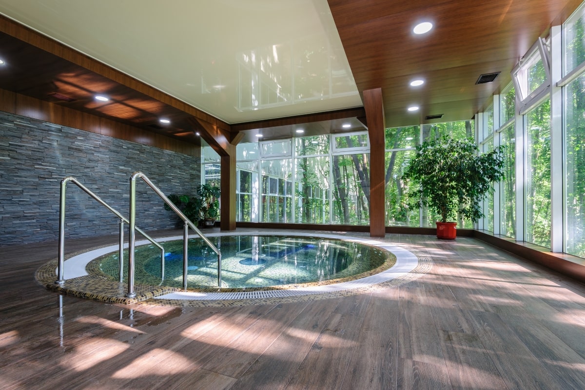 A fixed design enclosure for an round indoor pool, with custom features including glass windows and lighting.