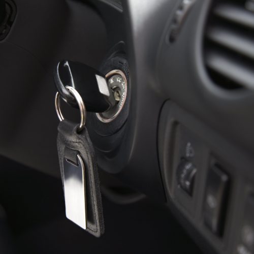 Car keys and fob dangling from car ignition.