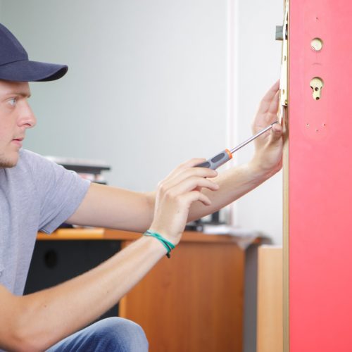 Mobile locksmith fixing red door lock.