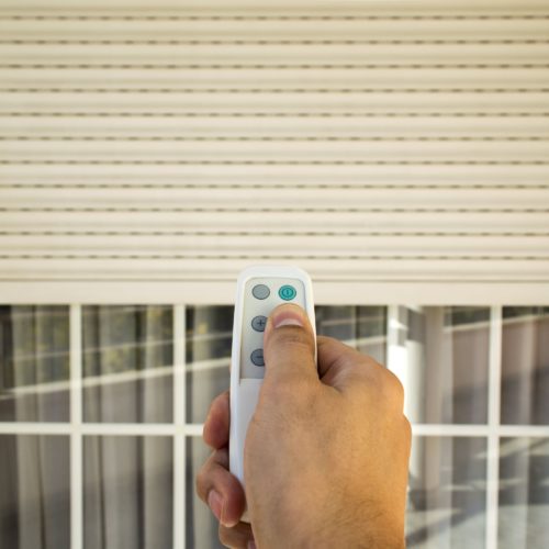 Secure roller shutters being closed by handheld electronic remote.