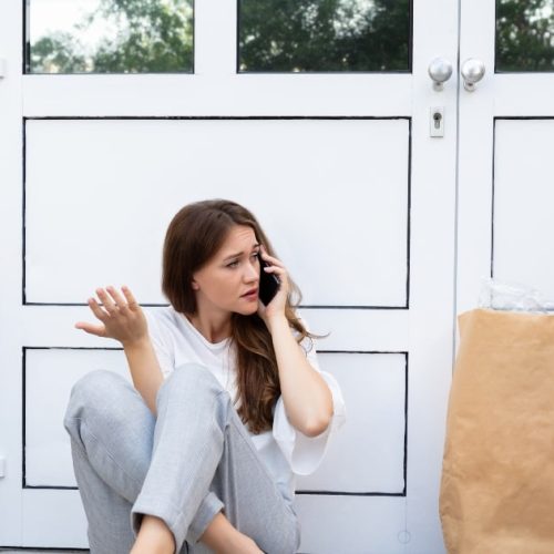 Woman sitting outside her entrance door locked out.