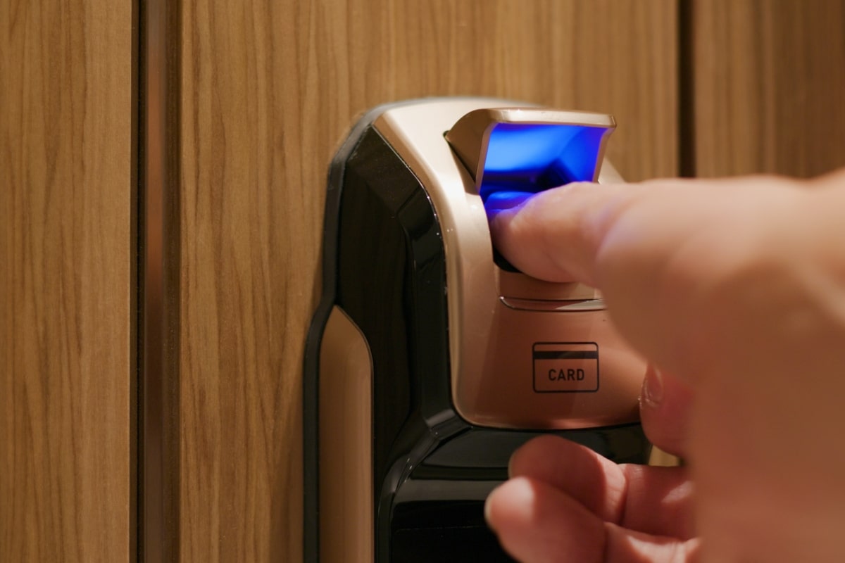 The image captures a moment of access being granted by a fingerprint scan on a sophisticated digital door lock, illustrating the ease of keyless entry.