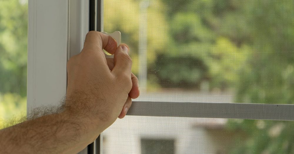 Man opening flyscreen security mesh at his home.