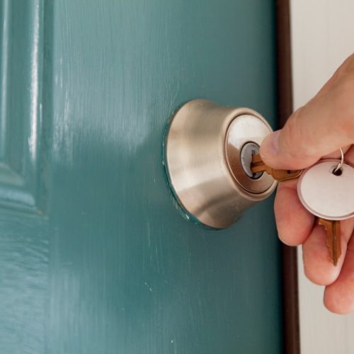 A deadlock key being turned in a lock set on a green door, showing the the additional layer of protection provided by installing deadlocks.