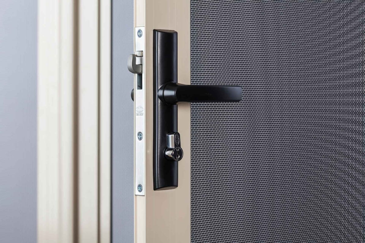 What Makes a Barrier Door Different From a Security Door? 4 A hinged door handle on a security screen door.