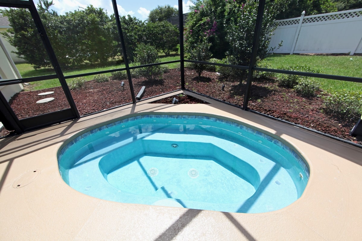 An outdoor spa enclosed with screens to allow sun in and keep bugs and leaves out.