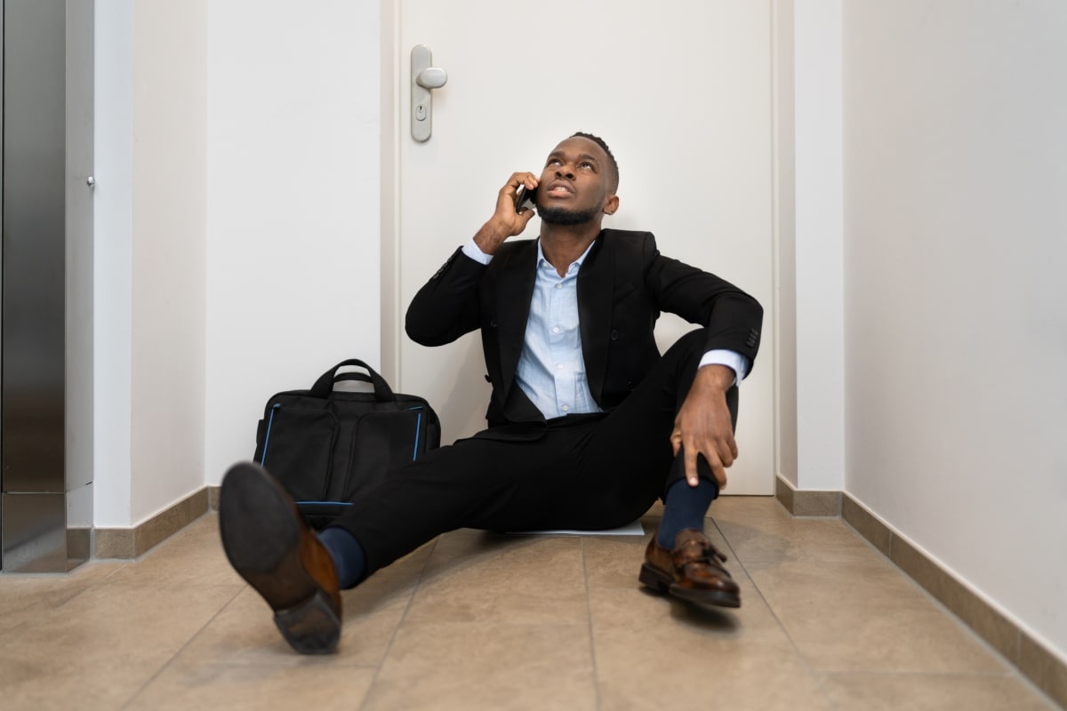 A well-dressed individual appears locked out and making a phone call, underscoring the advantages of having smart door locks to avoid lockout scenarios.