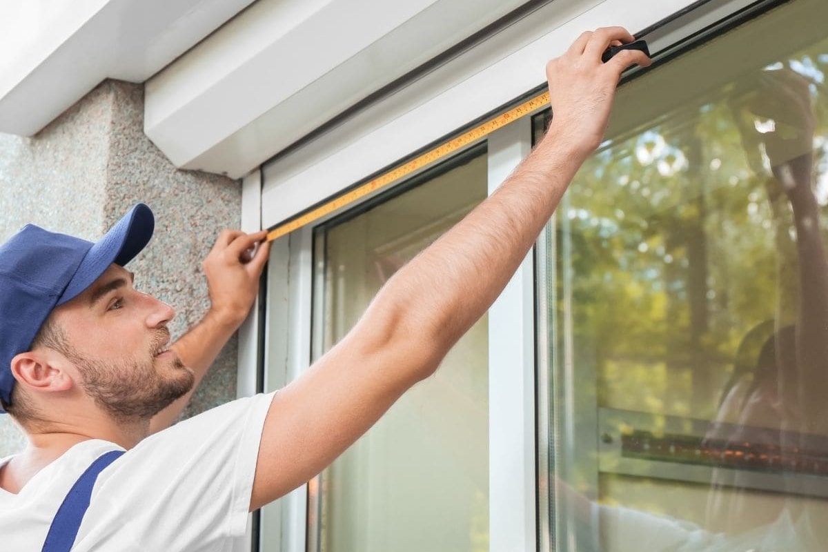 Installer measuring a window frame, a key step in fitting roller shutters.