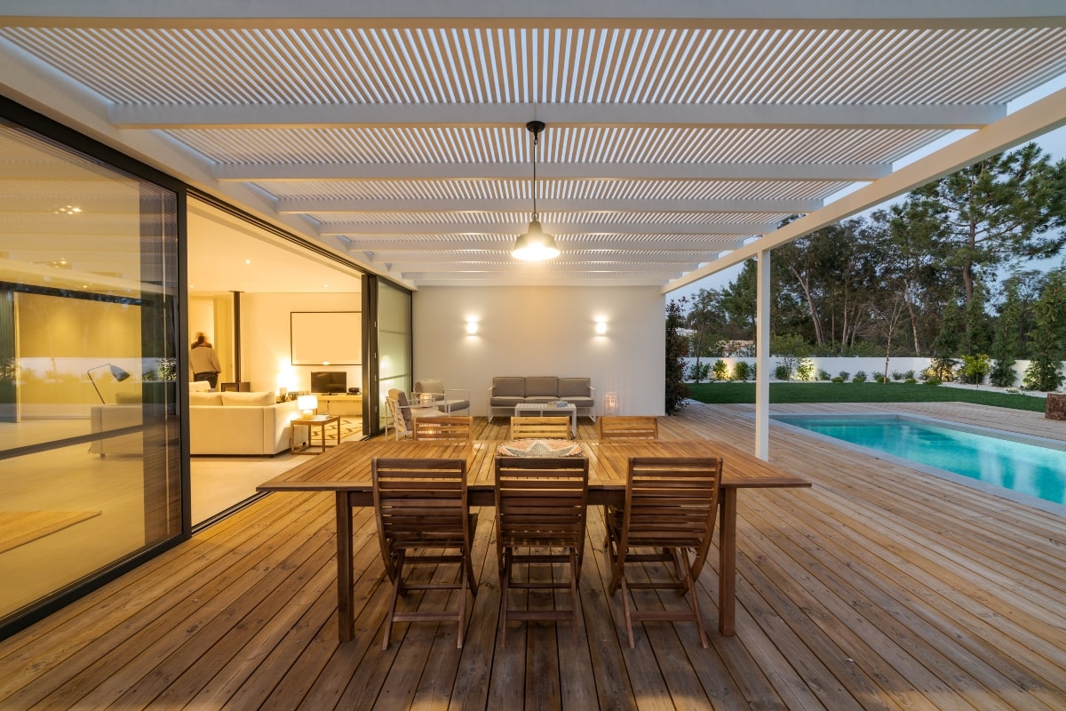 Covered outdoor living area with wood floors next to a pool.