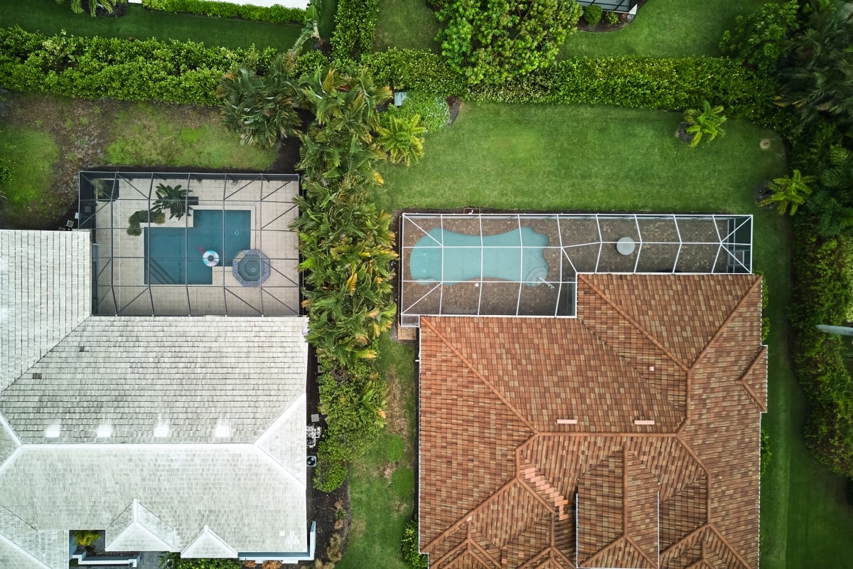 Aerial view of a properties showcasing modern patio screens, offering privacy and elegance to two outdoor pool areas.