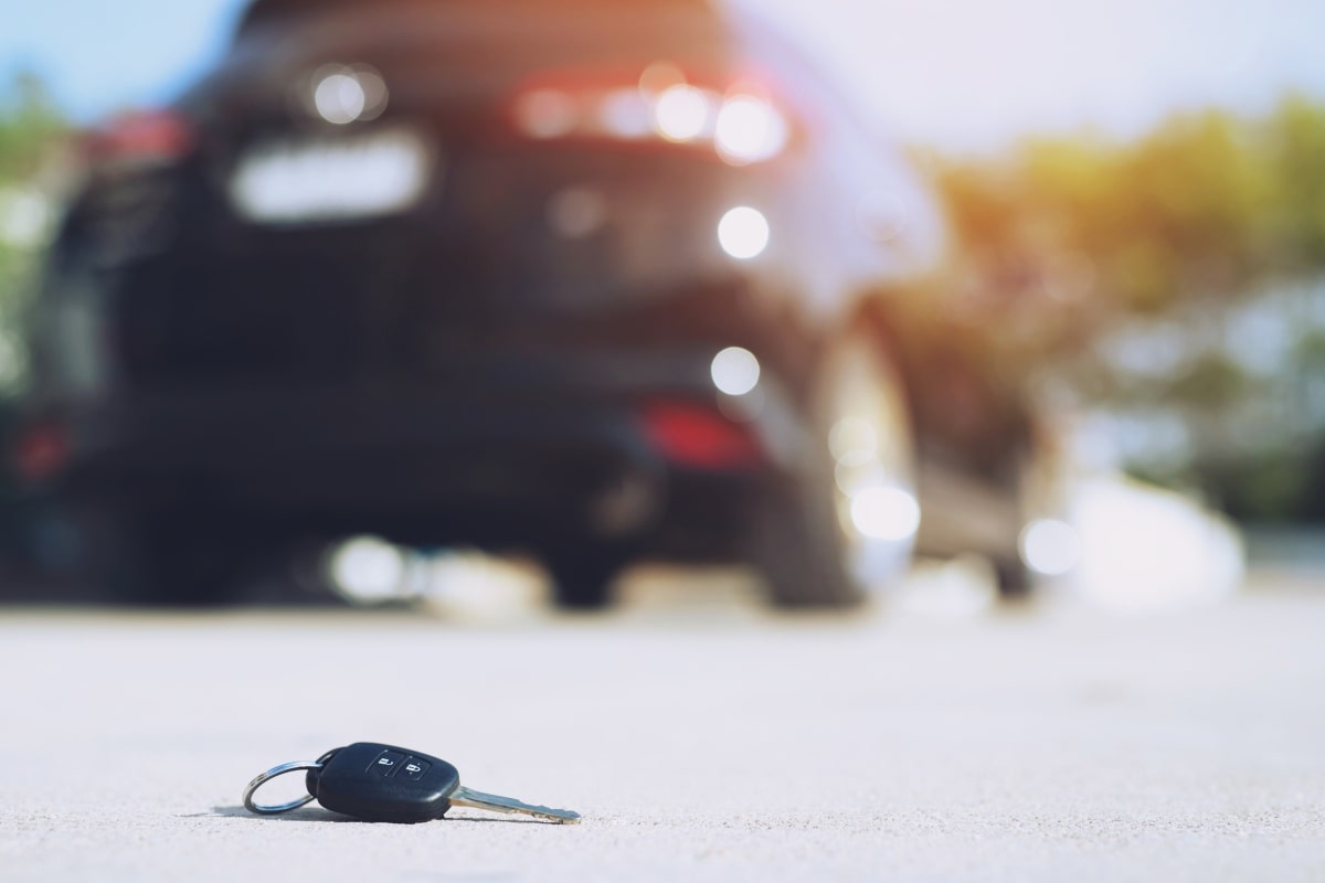 Enhancing Auto Security: How the Transponder Key Revolutionised Car Access 4 Low angle image of a transponder car key lying on the road with a blurry car in the background, illustrateing the concept of lost keys and the need for transponder key replacement.