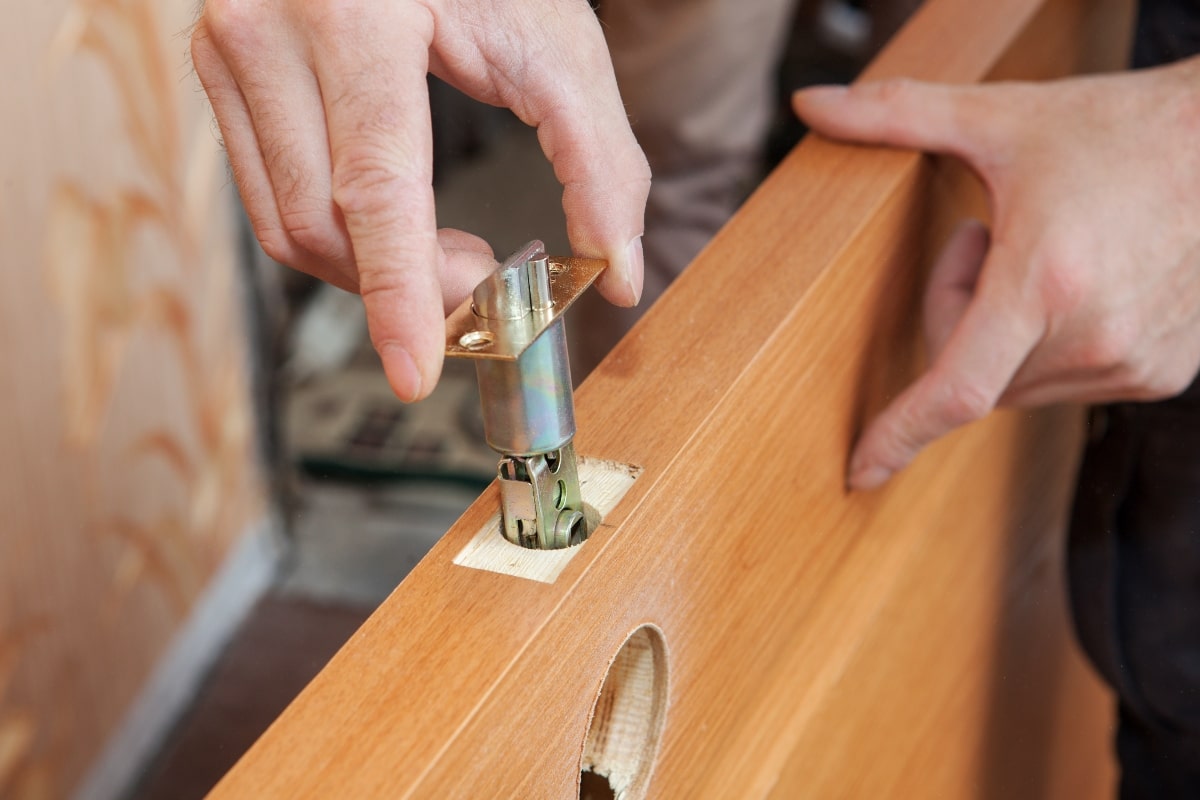 Professional locksmith installing new lock in a wooden door.