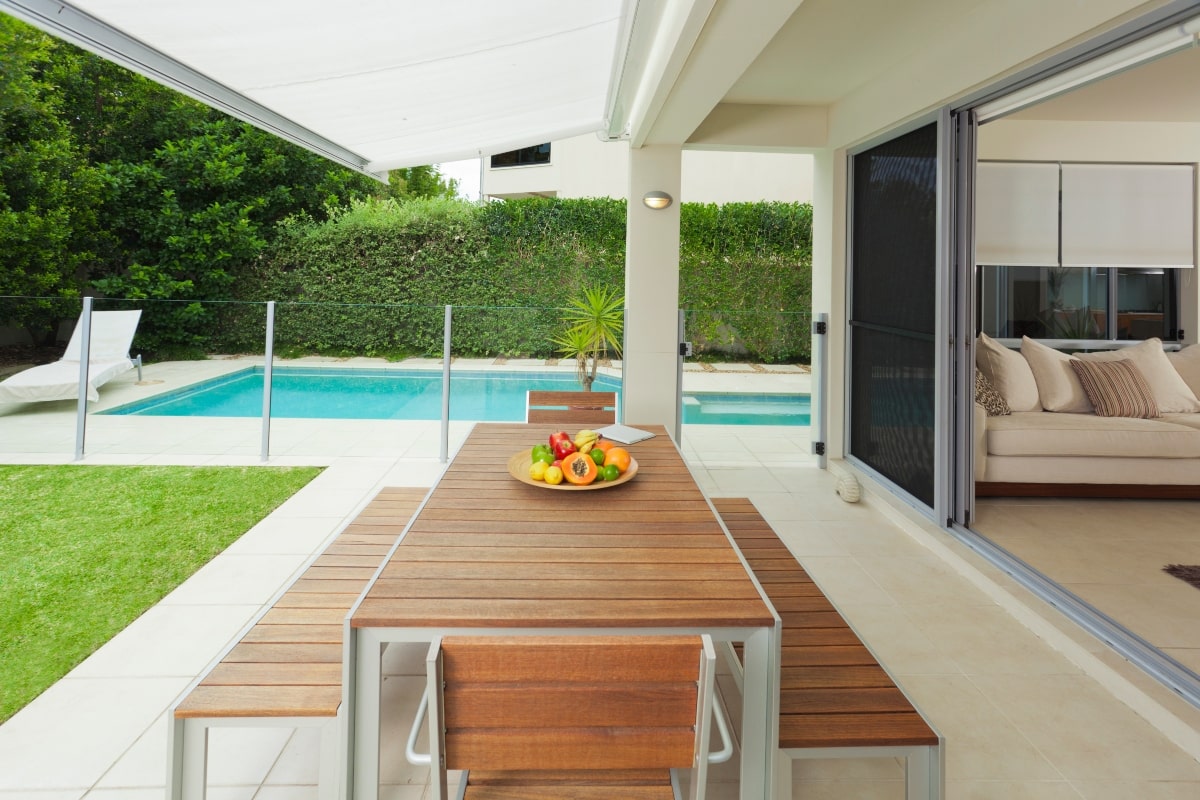 Outdoor pool area with open sliding doors to indoor living area.