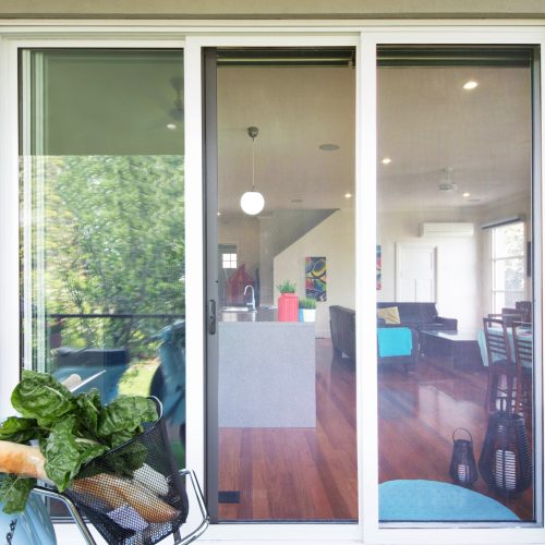 Secure mesh sliding door with white frame, offering ventilation and visibility into the home.