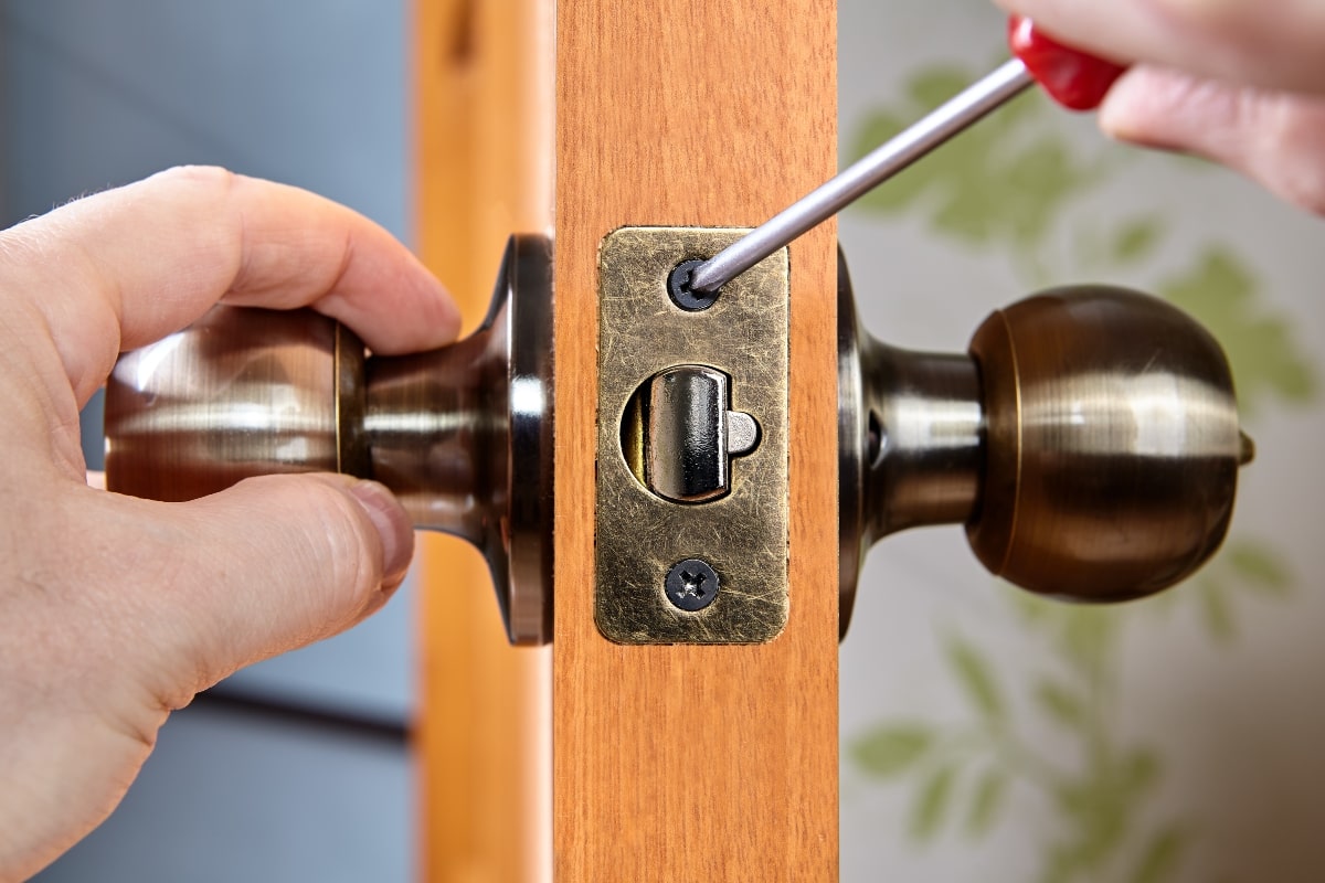Tightening strike plate screws in a door lock.