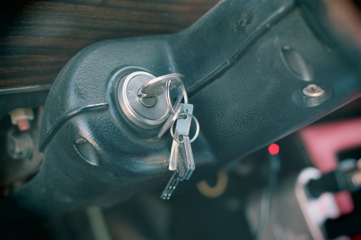 A close-up image of a traditional car ignition, with a standard metal key inserted. This image highlights the difference between standard car keys and modern transponder keys.
