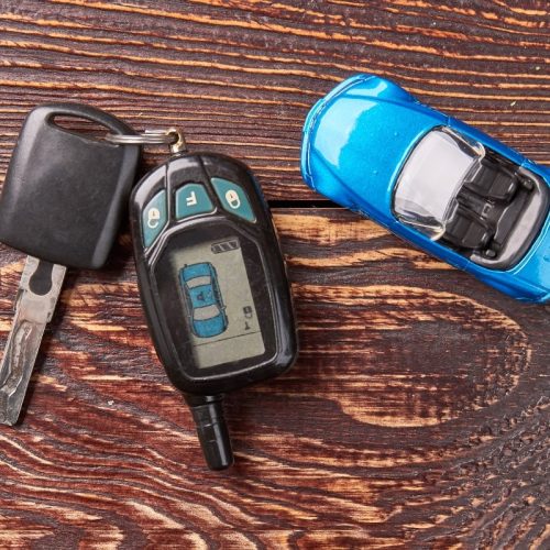 A close-up image of a transponder car key placed next to a blue toy car on a table.